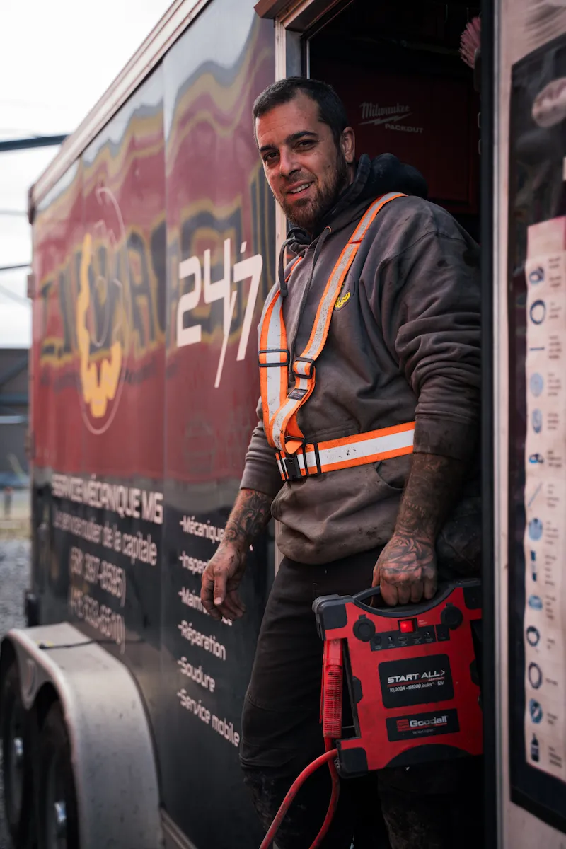 Mécanicien de Service Mécanique MG devant l'unité mobile avec un démarreur de secours